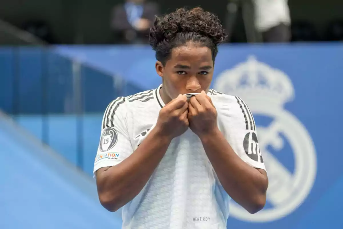 Jugador de fútbol besando el escudo de su camiseta en un estadio.