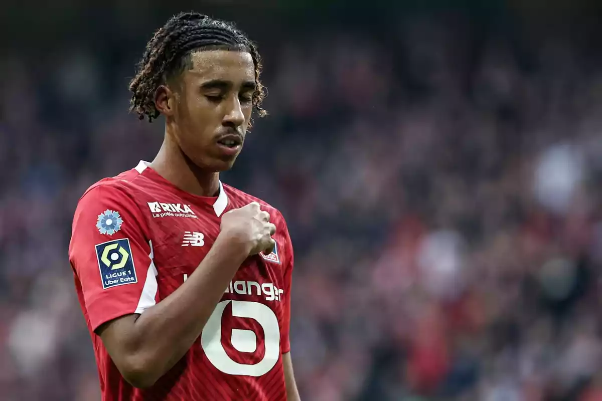 Jugador de fútbol con uniforme rojo del equipo Lille OSC en un estadio.