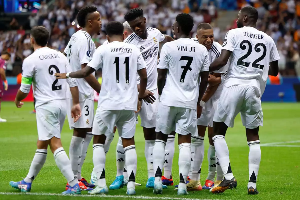 Jugadores de fútbol con uniformes blancos celebrando en el campo.