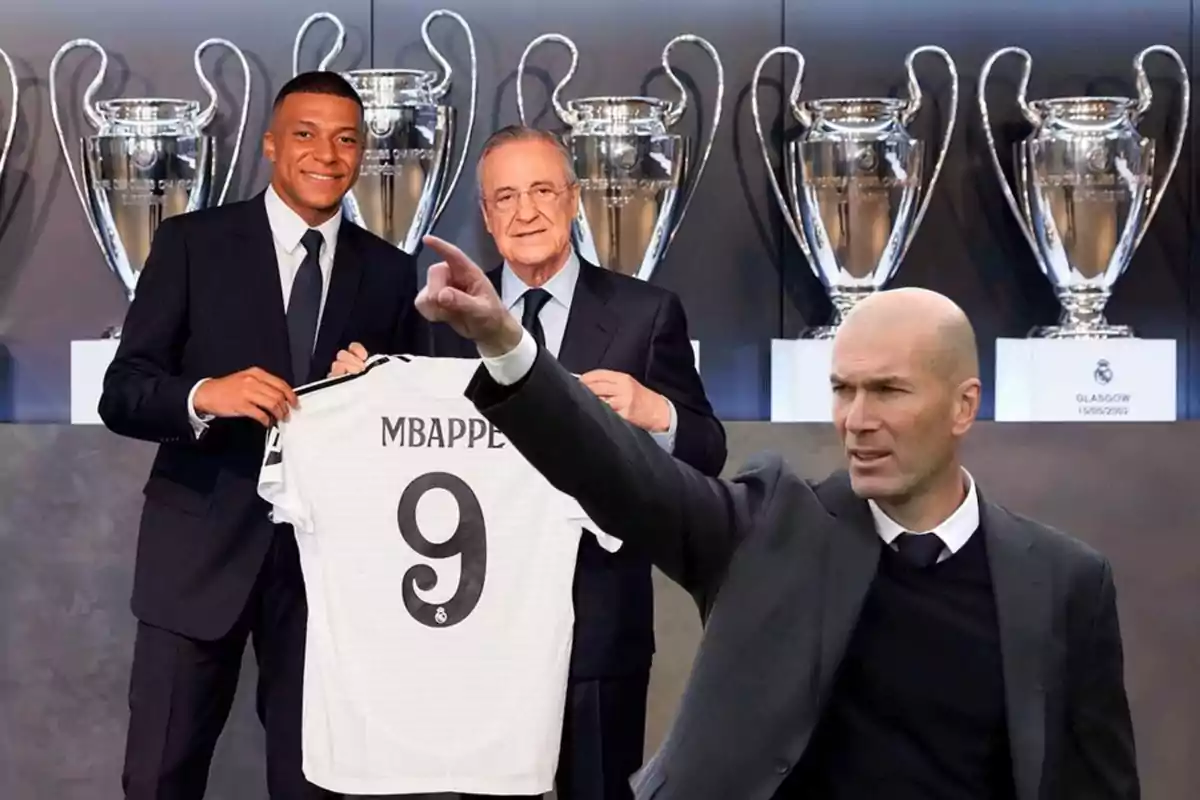 Tres hombres posan frente a trofeos de la Liga de Campeones, uno de ellos sostiene una camiseta con el nombre "Mbappe" y el número 9.