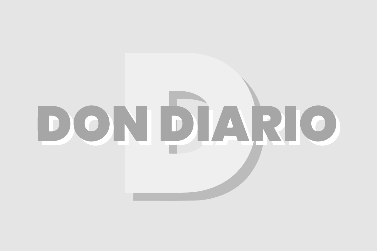 Un jugador de fútbol con una camiseta blanca y roja sonríe y levanta el dedo índice en un estadio lleno de espectadores, con el escudo del Real Madrid superpuesto en la imagen.